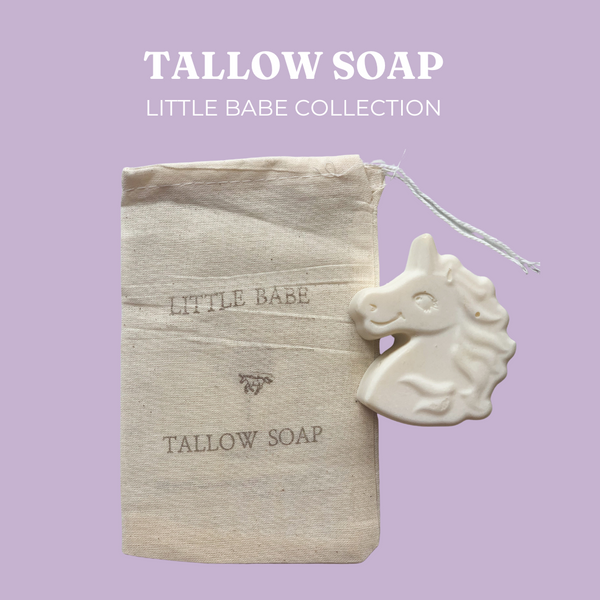Live Tallowed unicorn-shaped tallow soap from the Little Babe Collection, made with calendula-infused olive oil. A gentle, all-natural soap designed for delicate and sensitive skin. Displayed against a soft purple background and a natural linen bag with product branding.