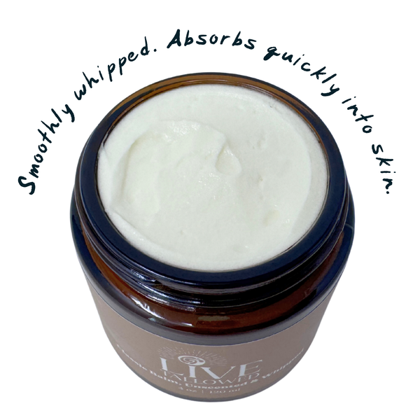 Top view of an open amber glass jar filled with whipped tallow balm, showcasing its light and creamy texture. Surrounding text reads 'smoothly whipped. absorbs quickly into skin.' on a white background.